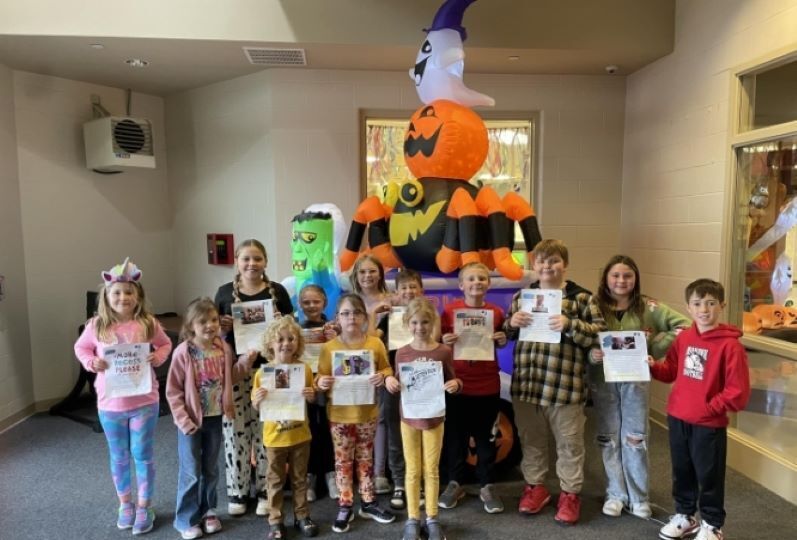 Group of kids with certificates in front of Halloween inflatables